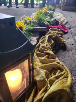 Leuchtende Laterne mit Kerze, gelben Blumen und goldenem Tuch als Teil einer festlichen Zeremonie.